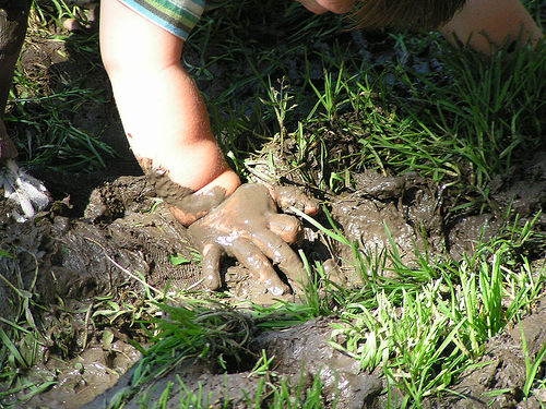 a small child plays in muddy ground